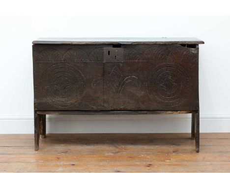 An oak six-plank coffer,17th century, the front with incised geometric roundels and floral decoration, on bench end supports,