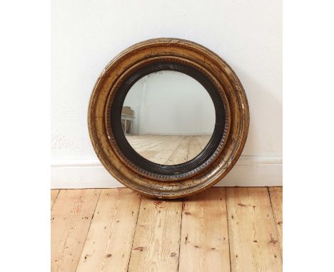 A Regency gilt-framed convex wall mirror,early 19th century, with a ribbon-tied deep frame and reeded ebonised slip,61cm diam