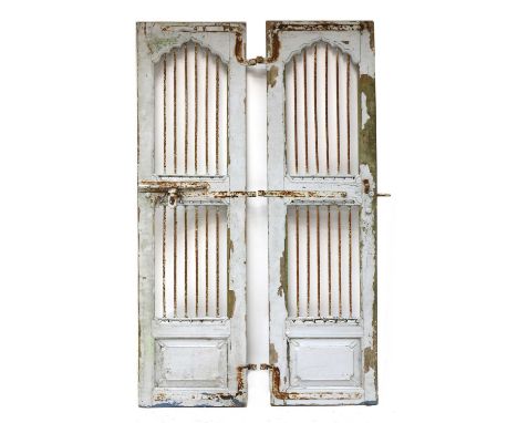 A pair of Indian painted teak and wrought iron doors, c.1900, each with a scrolling arched panel above two sets of six bars, 