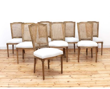 A set of eight modern bleached oak dining chairs,by Nordic Style London, each with a caned back and upholstered serpentine se