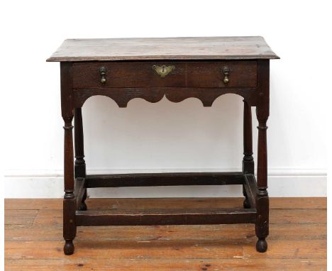 An oak side table, 18th century, the rectangular top above a single drawer and a shaped apron, raised on ring-turned supports