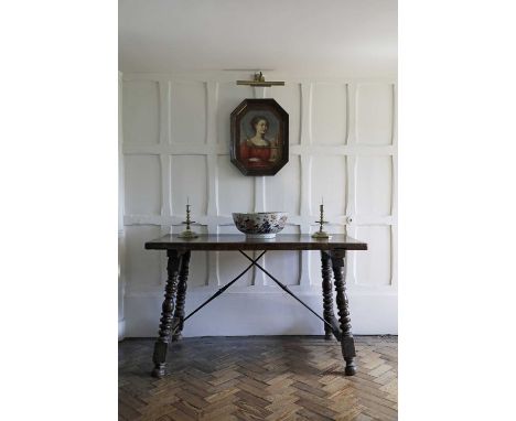 A Spanish walnut table,17th century, with heavy plank top, supported by ironwork stretchers and on ring-turned column legs,13