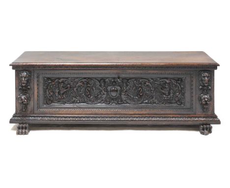 A walnut cassone, 17th century, Italian, with a richly-carved front panel depicting half-human figures and lions, an ironwork