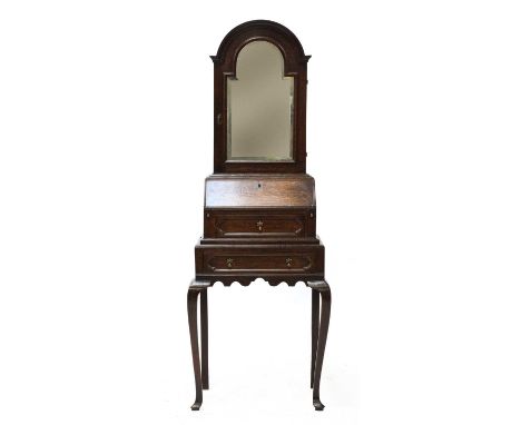 A diminutive oak dressing bureau,early 18th century, the dome-topped upper section with a single door, set with an arching be