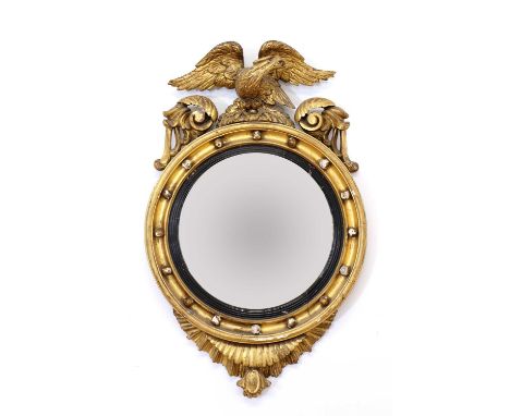 A Regency period circular gilt eagle wall mirror,with ball-mounted frame and ebonised fillet,62cm wide100cm high