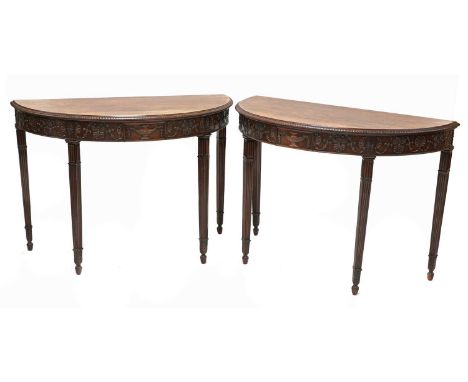 A pair of Adam Revival mahogany demilune console tables, c.1900, each with trailing anthemion and bell-flower carved decorati