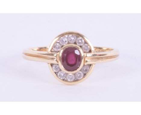 An 18ct yellow gold modern design cluster style ring set with a central oval cut ruby, approx. 0.37 carats, surrounded by sma