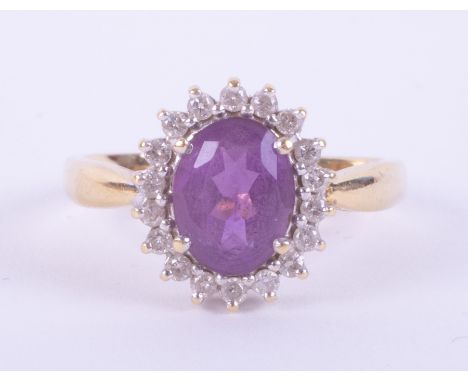 A yellow &amp; white gold (not hallmarked or tested) cluster ring set with a central oval cut amethyst, approx. 1.75 carats, 