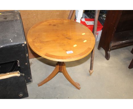 A reproduction yew wood circular topped side table raised on tripod base