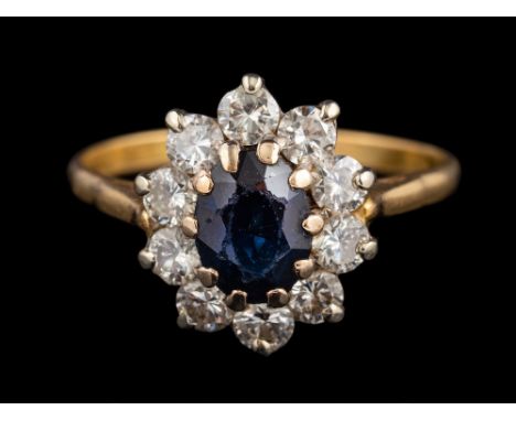 A sapphire and diamond cluster ring:, the central oval cut sapphire claw set within a surround of brilliant cut diamonds, rin
