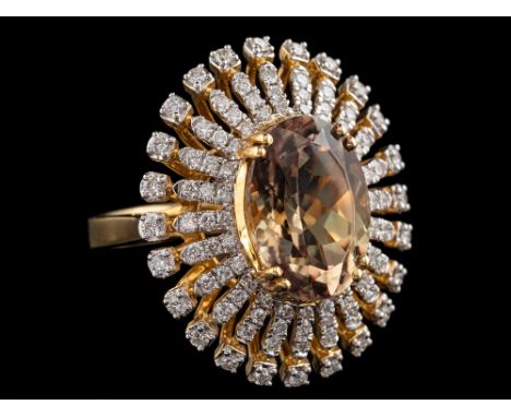 An 18 carat gold csarite and diamond ring:, the central oval cut csarite claw set within a surround of brilliant cut diamonds