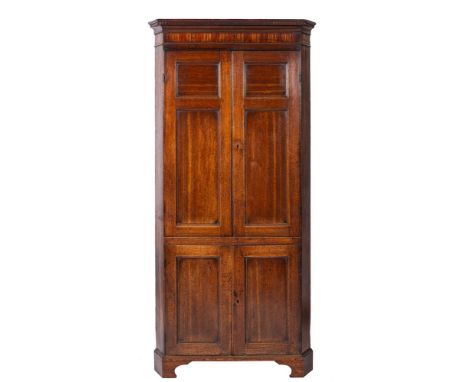 An early 19th Century oak standing corner cupboard:, with a moulded dentil cornice and inlaid simulated fluted frieze, enclos