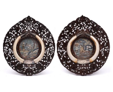 A pair of 19th century carved hardwood frames: centred with Chinese embroidered panels and enclosed with boar's tusks with si