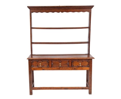 An oak dresser in the Jacobean taste:, the shelved superstructure with a moulded cornice and shaped fret cut apron, the base 