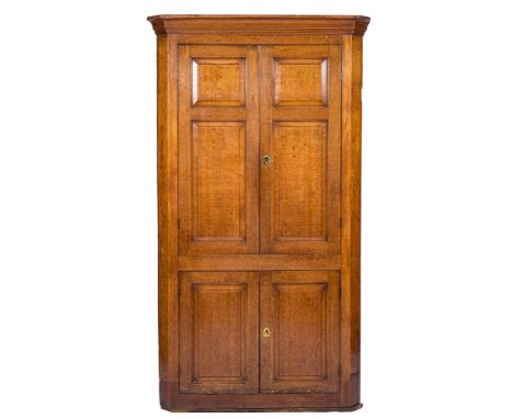 A late 18th Century oak standing corner cupboard:, with a moulded cornice and canted angles, enclosed by a pair of fielded pa