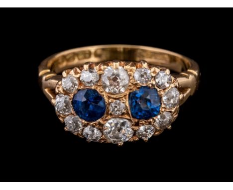 An Edwardian sapphire and diamond ring,: the two circular cut sapphires within old cut diamond set surrounds, approximately 0