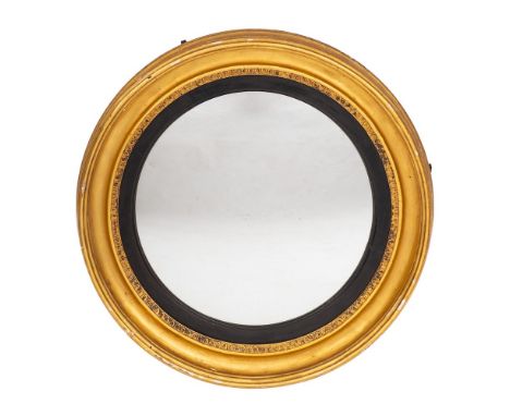 An early 19th Century giltwood circular convex mirror:, the plate within an ebonised slip and foliate, moulded and reeded sur