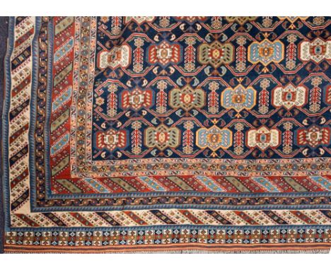 A Shirvan carpet:, the indigo field with an all over geometric design, enclosed by rust and ivory diagonal striped borders,, 