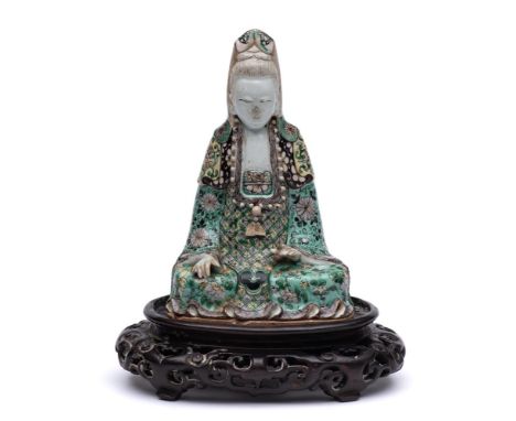 A Chinese famille verte biscuit figure of Guanyin: seated cross-legged, her face with gentle smile, wearing flowing robes dec