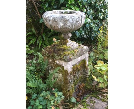 A carved stone pedestal garden urn:, the circular bowl with alternate lion masks and rosettes with acanthus and fluting below