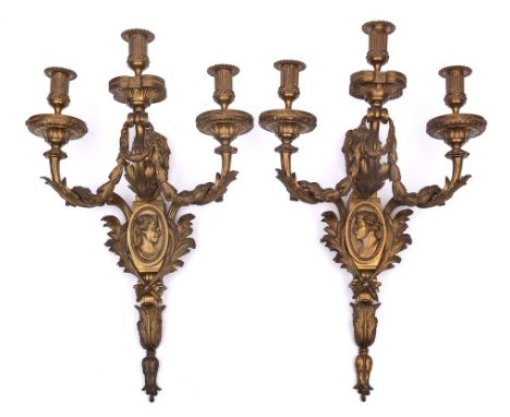 A  pair of gilt ormolu three-branch wall appliques: the urn-shaped nozzles decorated with acanthus leaves on scrolling branch