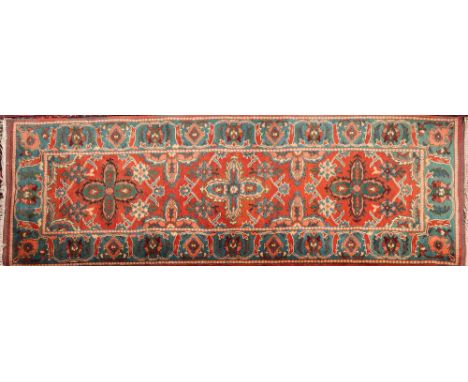 An Iranian runner:, the brick red field with triple geometric flowerhead medallions, enclosed by a main pastel blue cartouche