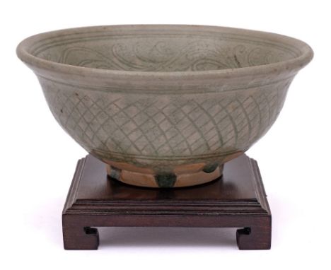 A Thai Sawankhalok celadon glazed bowl: the interior incised with a band of scrolling foliage within line borders, the exteri