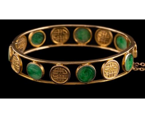 A jadeite bangle,: the hinged bangle with carved circular jadeite jade panels and circular panels with script, 5.5cm wide