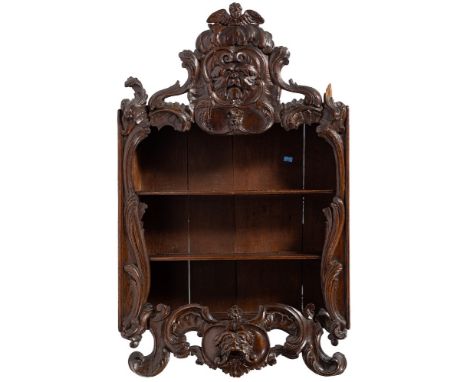 A 19th Century carved oak hanging open cabinet:, the fixed shelves within a cartouche acanthus scroll surround, with animal m