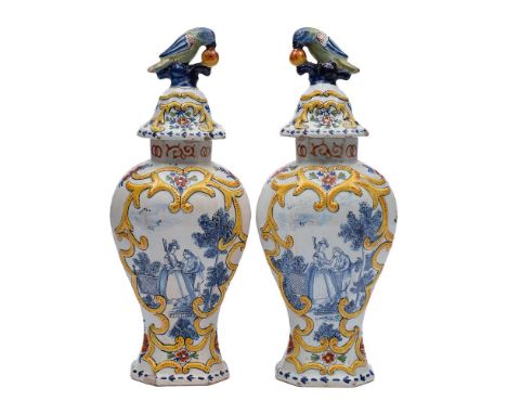A pair of Dutch polychrome delftware vases and covers: with parrot and fruit finials, painted with flowering branches and fig