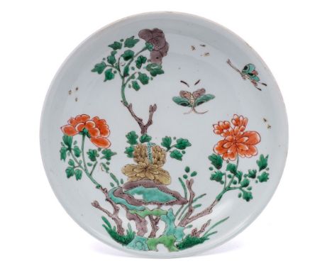 A Chinese famille verte saucer dish: painted with two butterflies flying above tree peonies issuing from green and aubergine 