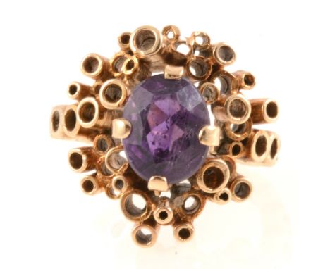 A contemporary dress ring set with an oval faceted amethyst 10mm x 7mm, four claw set in an all yellow gold (not hallmarked) 