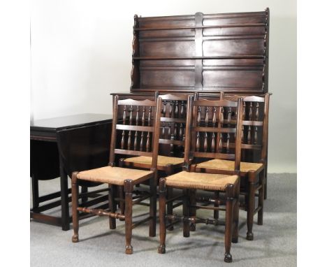 An Ercol dark elm dresser, 132cm, together with a matching drop leaf table and a set of four rush seated spindle back dining 