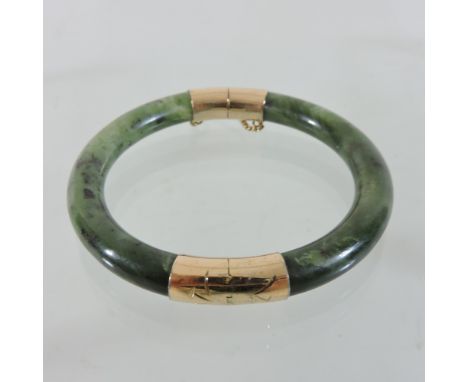 A 14 carat gold and jade bangle