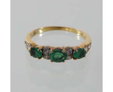 An 18 carat gold diamond and emerald half hoop eternity ring