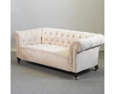 A 1920's cream upholstered Chesterfield sofa, with a buttoned back, on castors, 183cm