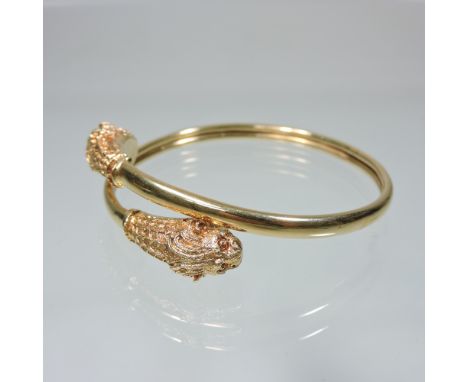 A ladies bangle, of overlapping leopard head design, marked 18 carat, 7cm diameter, cased
