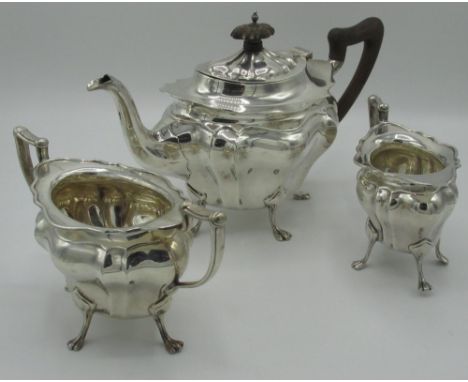 Geo.V hallmarked silver three piece tea service, with lobed ovoid bodies on four paw feet, tea pot with wooden handle and fin