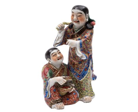 A Chinese famille rose group of the laughing Hehe Erxian twins wearing colourful robes, one opening a bowl and cover to revea