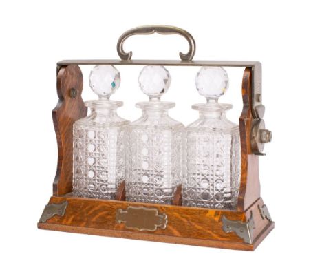 A Victorian oak and silvered metal mounted three-decanter tantalus, late 19th century, the mounts stamped Betjeman Patent, th