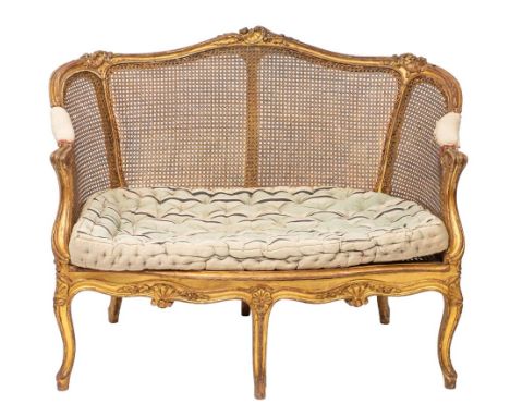 A giltwood and canework settee in Louis XV style, late 19th /early 20th century; the channeled toprail with scrolling foliate