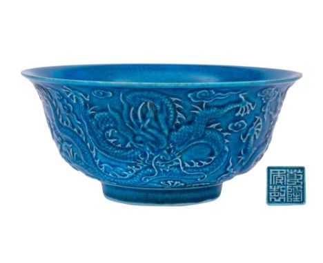 A Chinese blue ground 'Dragon' bowl: the exterior decorated in relief with three scally dragons amongst cloud and flame scrol