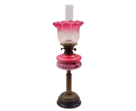 An Edwardian cranberry glass and brass paraffin lamp, circa 1900, with flared, etched shade and enamelled pink-tinged glass r