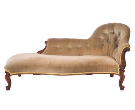 A Victorian mahogany and velvet upholstered chaise longue, circa 1870; with button back above scrolling foliate carved ends; 