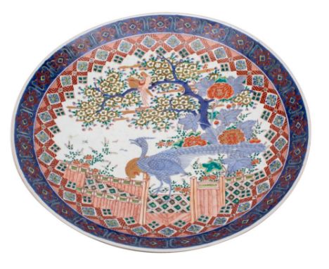 A large Japanese Arita charger decorated in under glaze blue, red, green and yellow enamel with a pair of pheasants in a gard