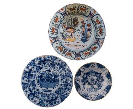 A mixed lot of Dutch delftware comprising four blue and white chargers and a plate variously painted with a basket and vases 