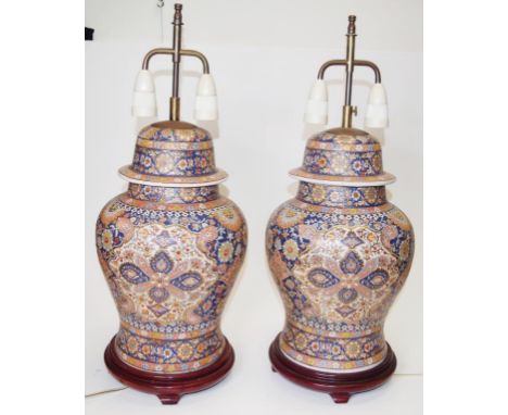 Good vintage pair Chinese ceramic table lamps each with extensive decoration, with twin electric connection, on carved wood b
