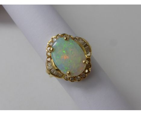 A Lady's 14 K Yellow Gold Diamond and Opal Ring, the opal 15 x 11 mm surrounded by 48 pts of baguette and 28 pts of round bri