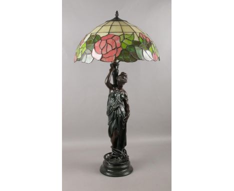 A large table lamp with Grecian female figure and Tiffany style shade.  H: 80cm.  Will need a plug. Some cracks and missing p