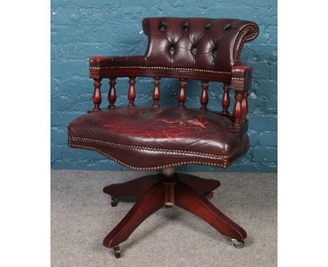 A deep button and studded Captain's swivel chair, in ox blood leather.  Tears to the leather.